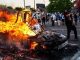 a protester stands next to a burning police car during the george floyd riots in minnesota