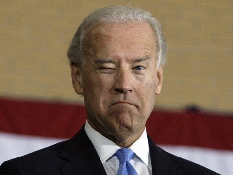 joe biden winking at camera in front of american flag