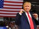 trump standing in front of american flag with his fists up in a boxing pose