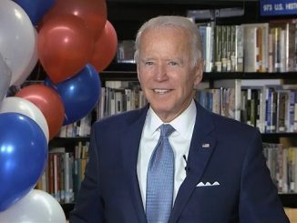 joe biden standing next to some balloons while accepting the 2020 democratic nomination in his basement