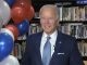 joe biden standing next to some balloons while accepting the 2020 democratic nomination in his basement