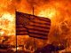 american flag flying in front of a burning fire