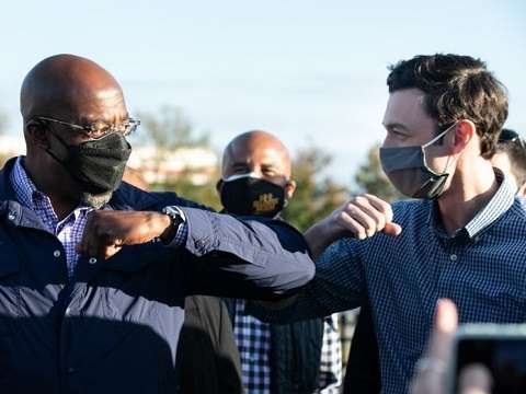raphael warnock and jon ossoff bumping elbows in covid masks